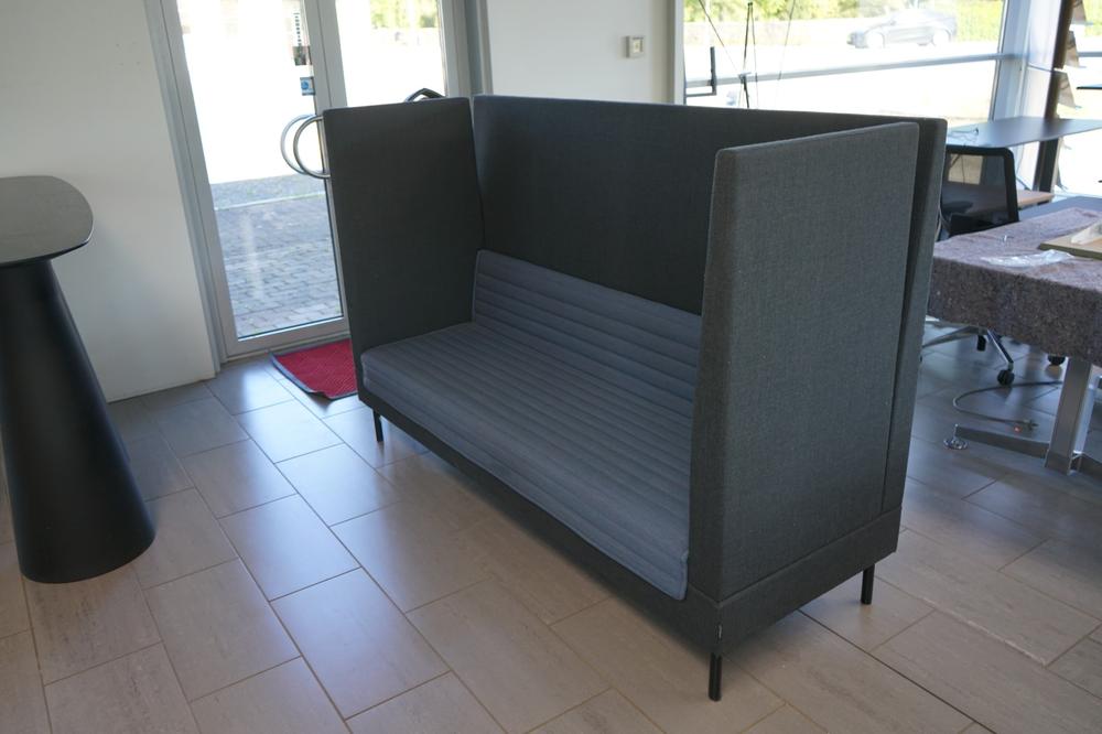 Offect Work sofa i grå med blå lydabsorberende akustikvægge, set i skrå vinkel. Moderne samtalesofa med høj ryg til kontor og lounge.